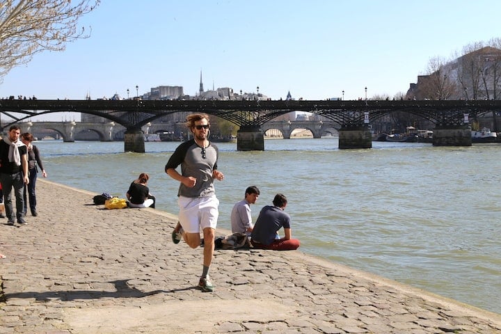 Jogging in Paris is very popular, especially along the River Seine in the sunshine, like this man in sunglasses, white shorts and a gray t-shirt.