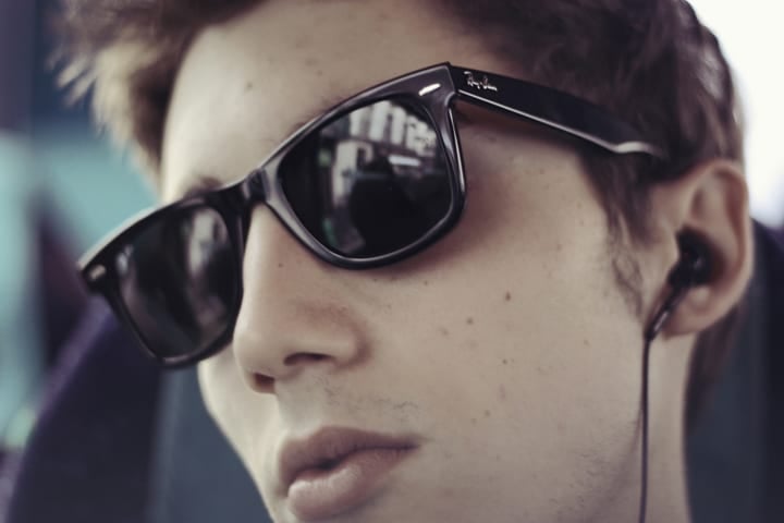 Raising Teens in Paris is about letting them have their style, like this boy wearing sunglasses and listening to music.