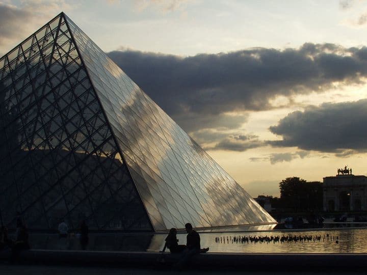 Finding a French boyfriend or girlfriend is easy online, and can lead to real-life dating, like for this couple sat by the glass pyramid of the Louvre Museum in Paris as night falls.