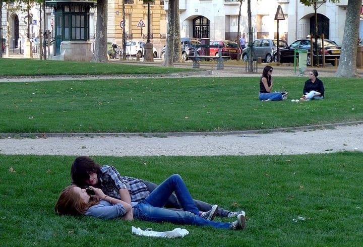 Online Dating in Paris can lead to real-life dating like for this couple lying on the grass of a city park.