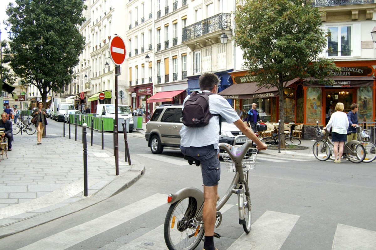 Ciclista na faixa de pedestres em Paris em um dia de verão. 