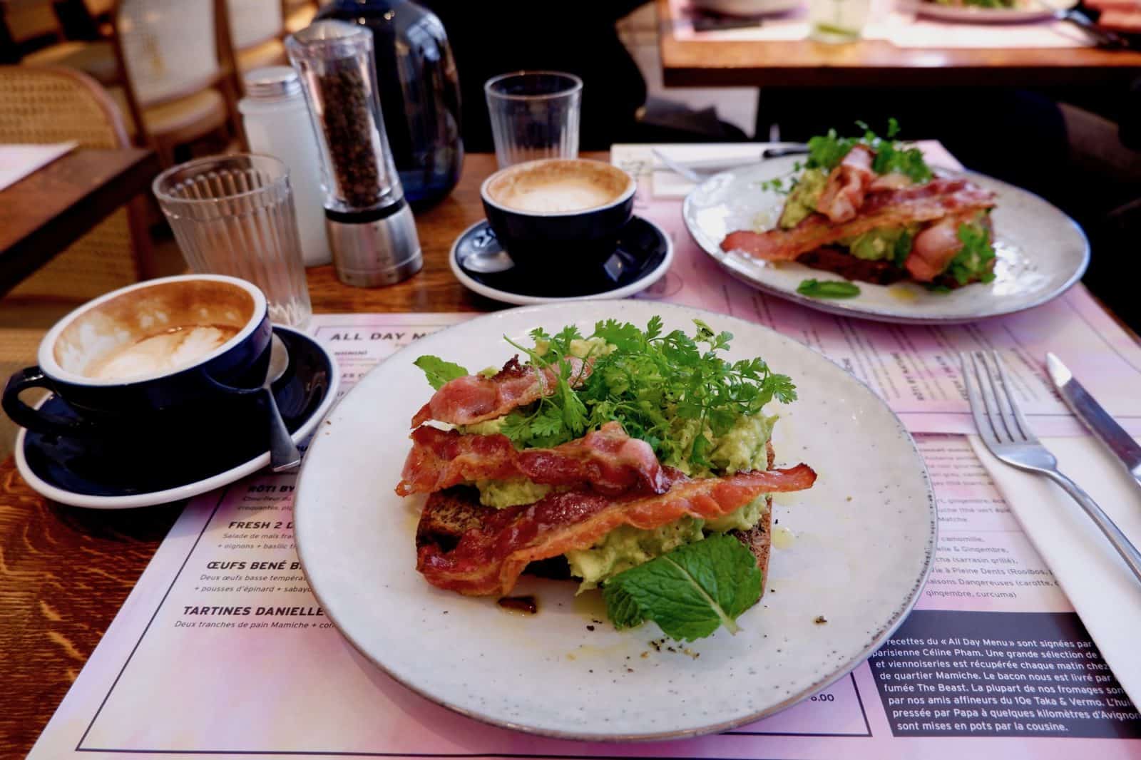 Coffee and avocado toast with crispy bacon brunch at Papilles coffee shop in Paris.
