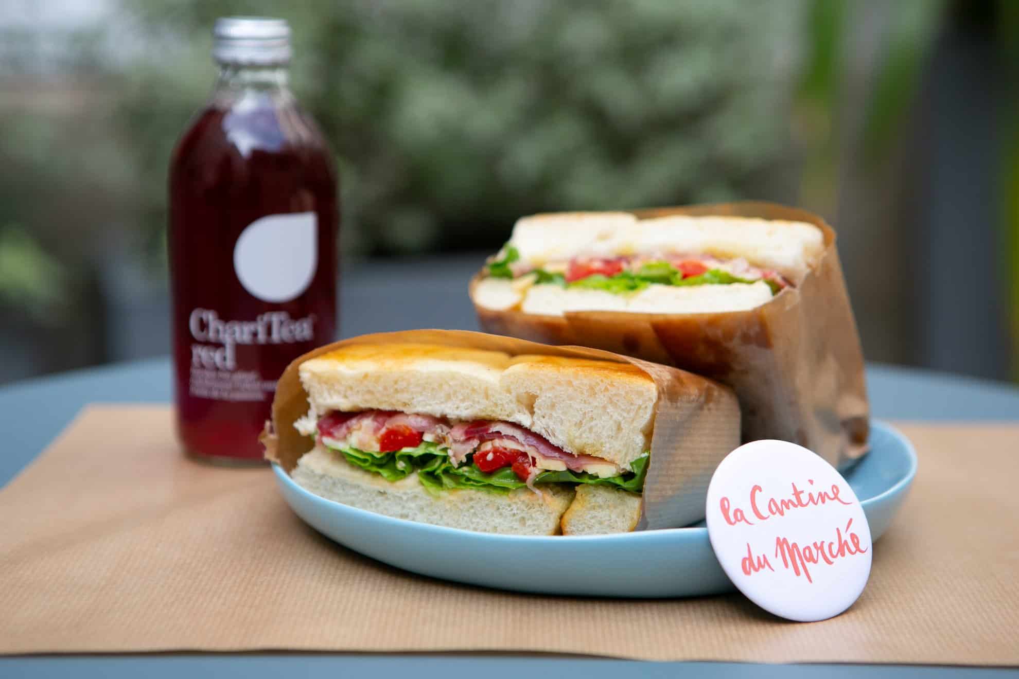 Sustainable food in Paris at La Cantine du Marché, where they serve fresh-pressed juices and teas like this Chari Tea, and homemade ham salad sandwiches on a blue plate.