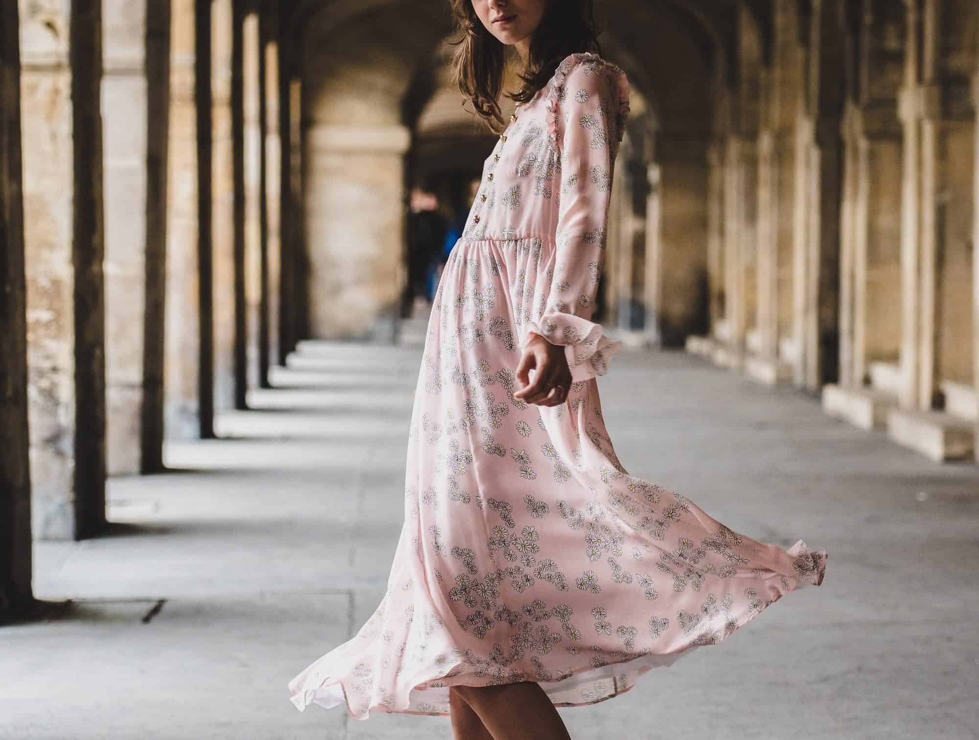 Luxury shopping in Paris made easy with these tips, including how to find stylish bohemian dresses like this one on a woman standing under the arches of the Palais Royal Gardens.