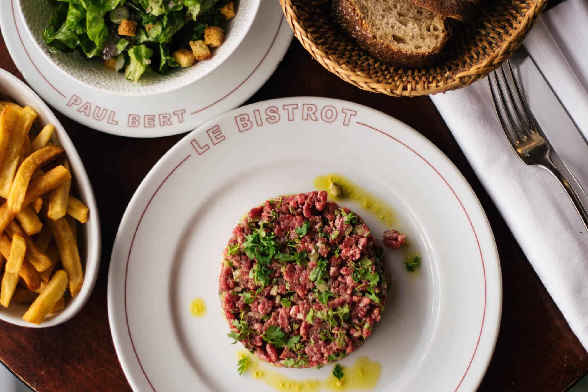 Signature steak tartare at the Bistrot Paul Bert in Paris with sides of bread, salad and fries.