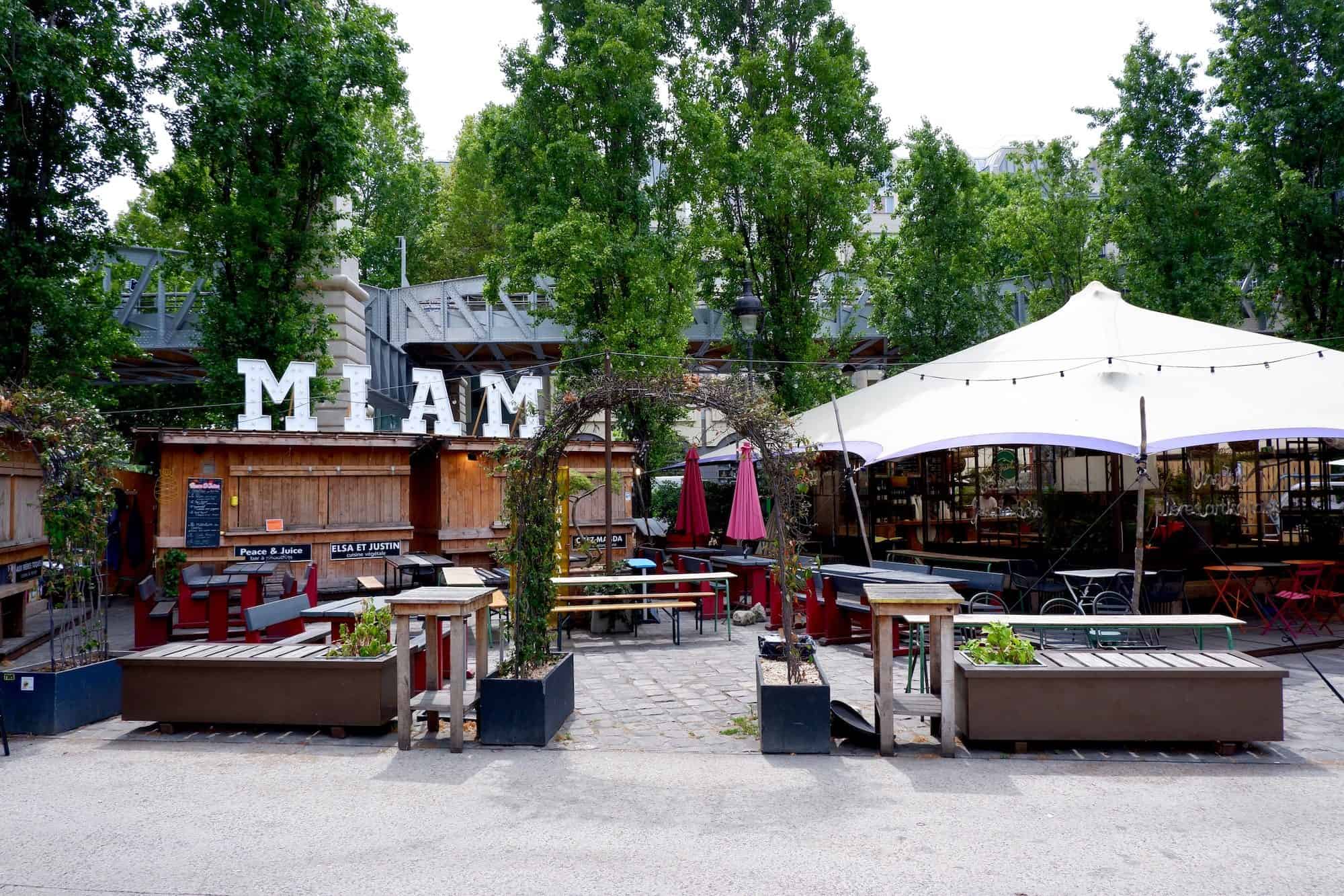 The terrace of La Rotonde Paris bar close to the canal is an urban garden with seating and parasols.