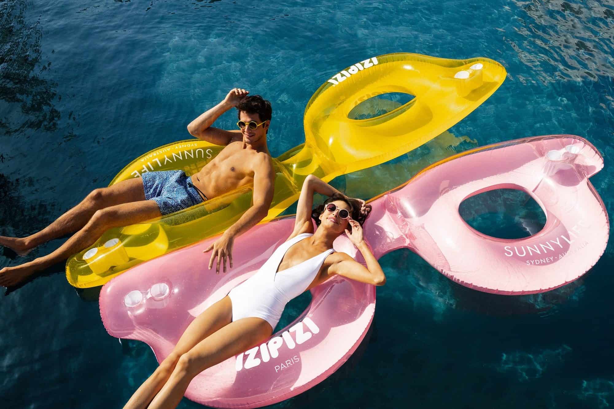 French brand IZIPIZI creates trendy and youthful glasses and sunglasses for women, men, kids and babies like those worn by this man and woman floating on huge floats in the shape of glasses on the sea.