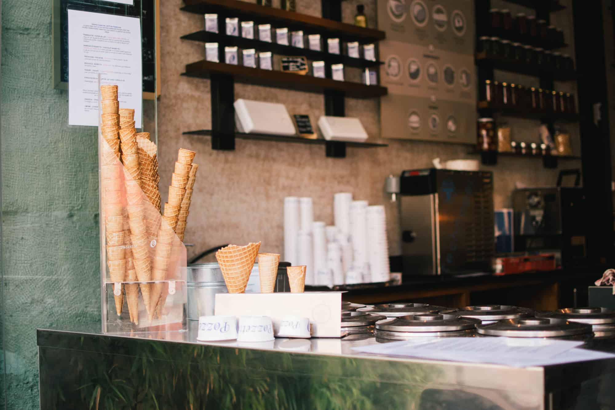 An ice cream counter with cones stacked on top.