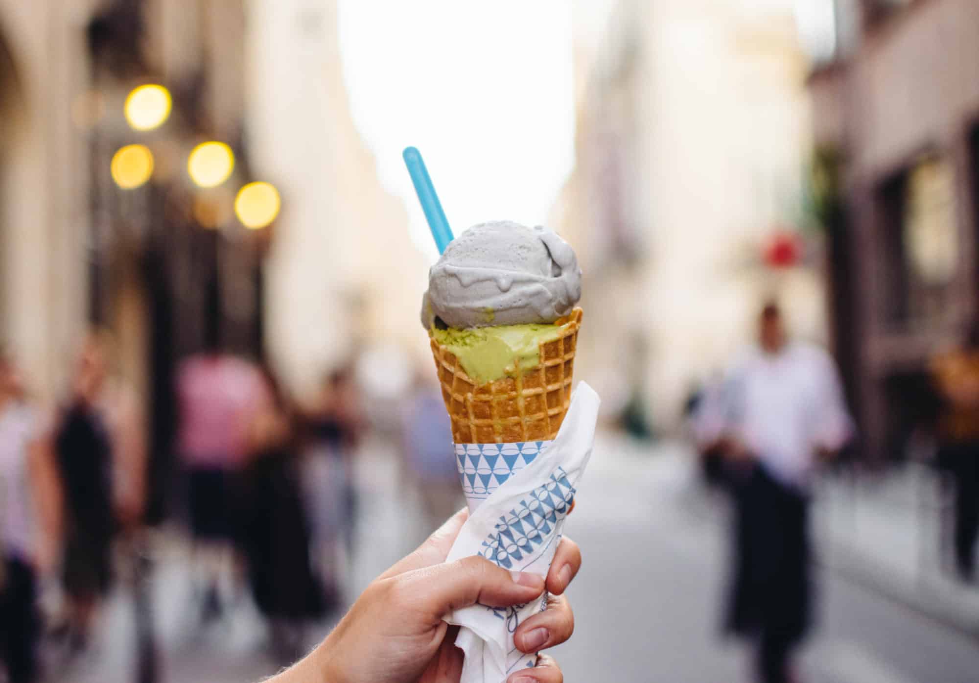 Two scoops of ice cream fro mUne Glace à Paris beingheld up by a person's hand in the streets of Paris.