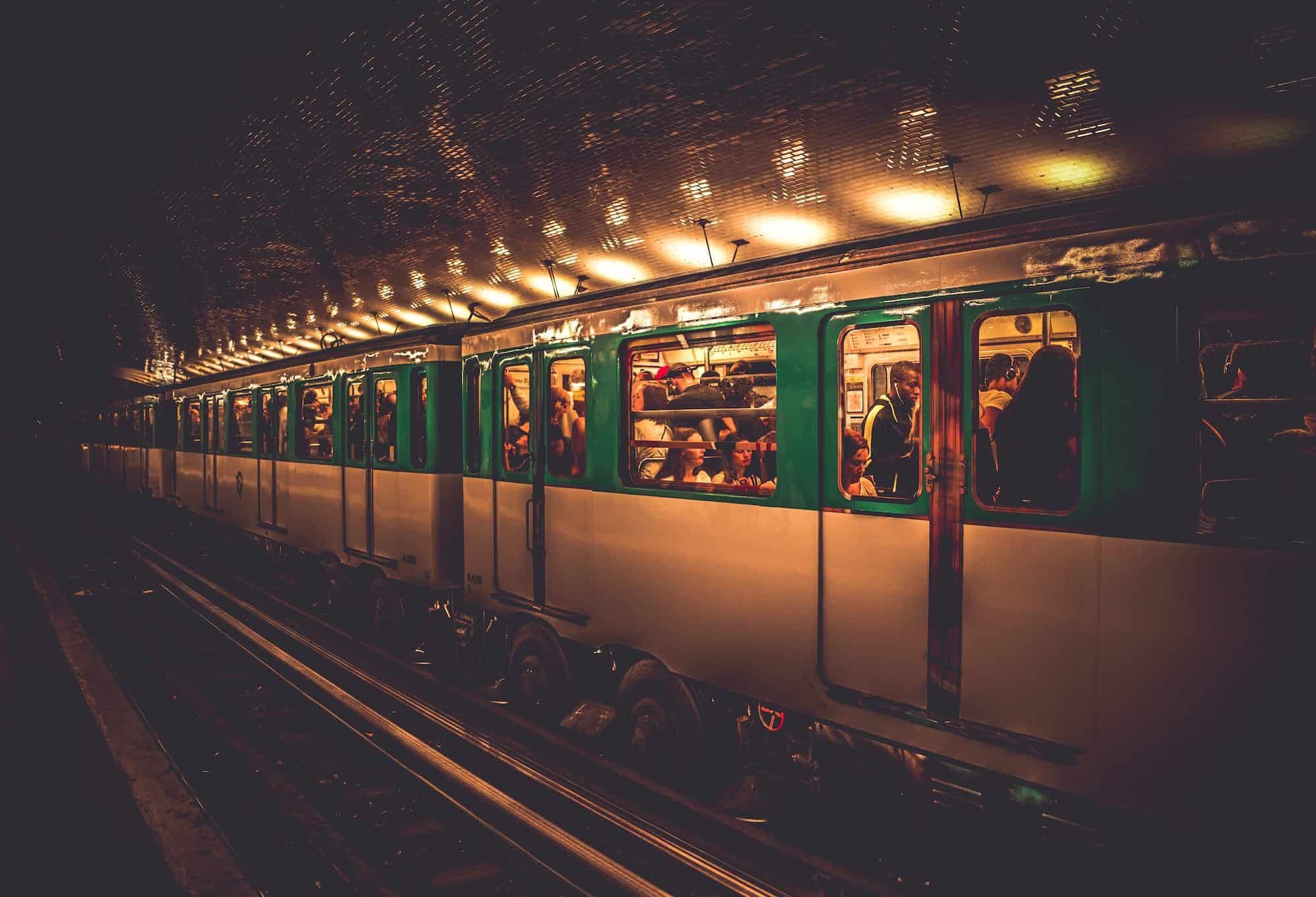 A metro pulling in at a metro station in Paris with passengers seen through the windows.