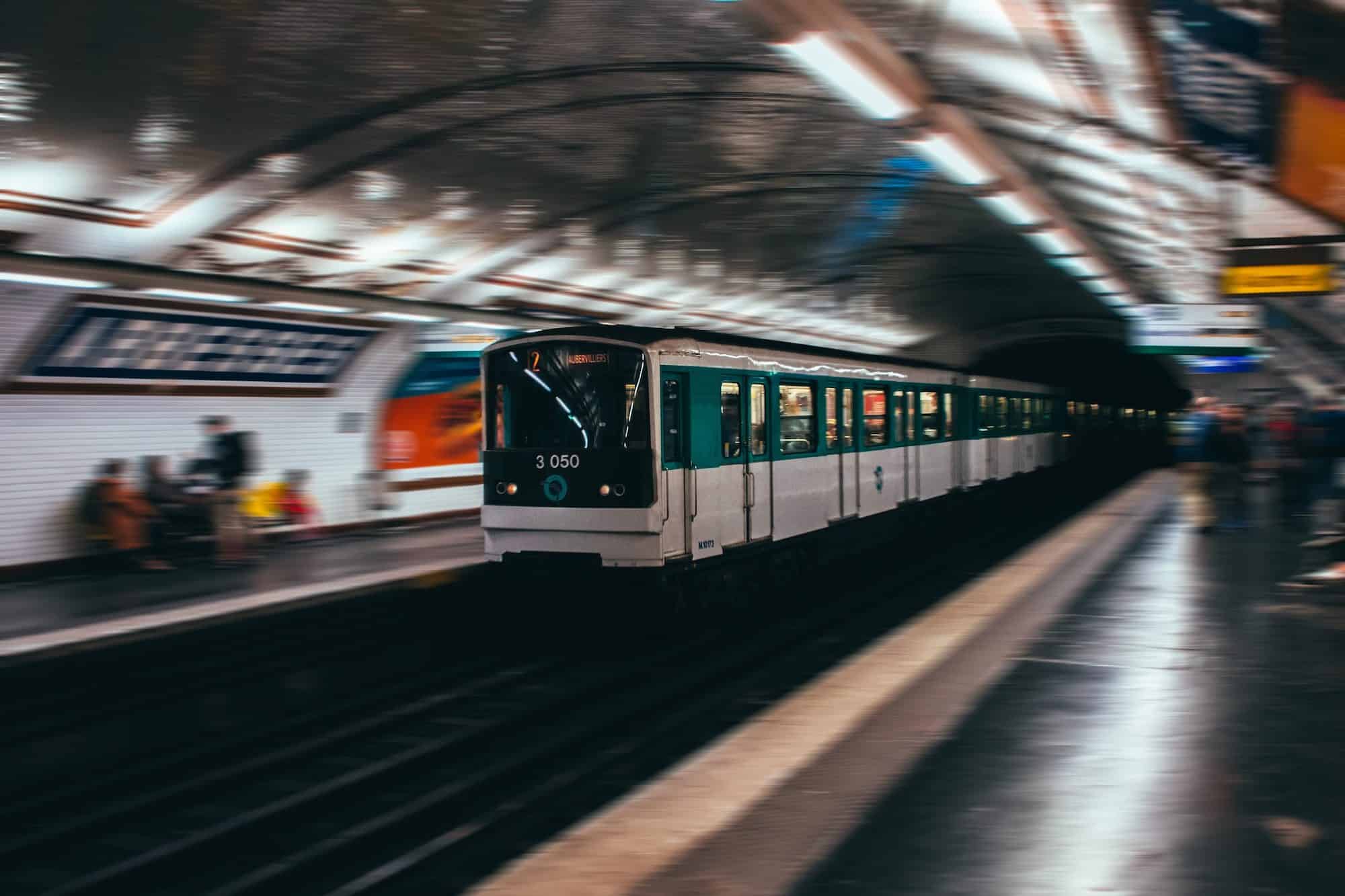 A metro train pulling in at Abbesses metro station. The train is the only thing in focus while the rest of the image is blurry.
