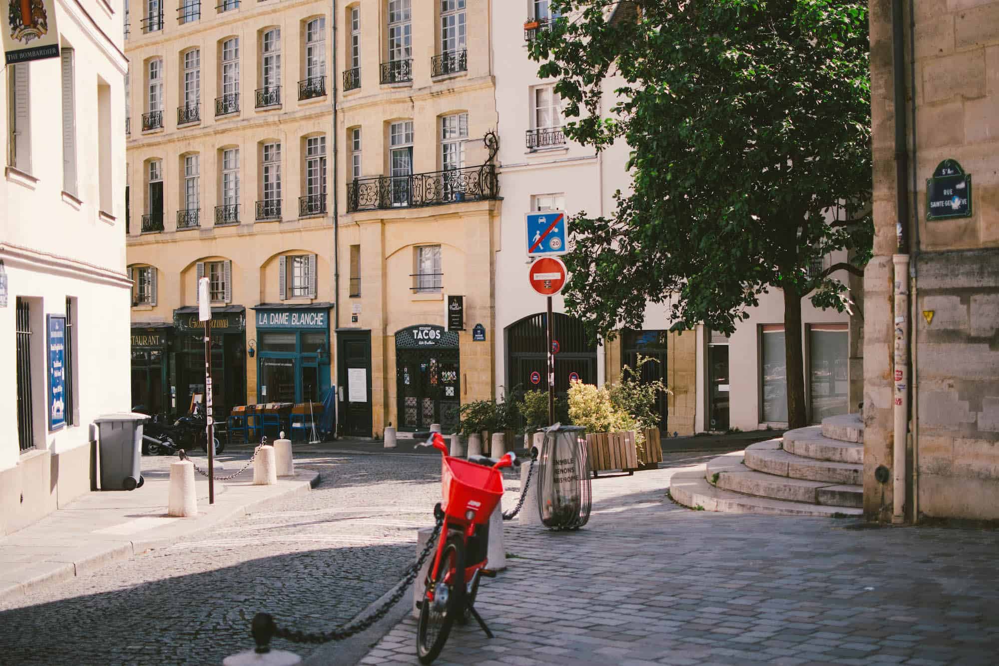 A cobblestone street in Paris with a red bike in the foreground.