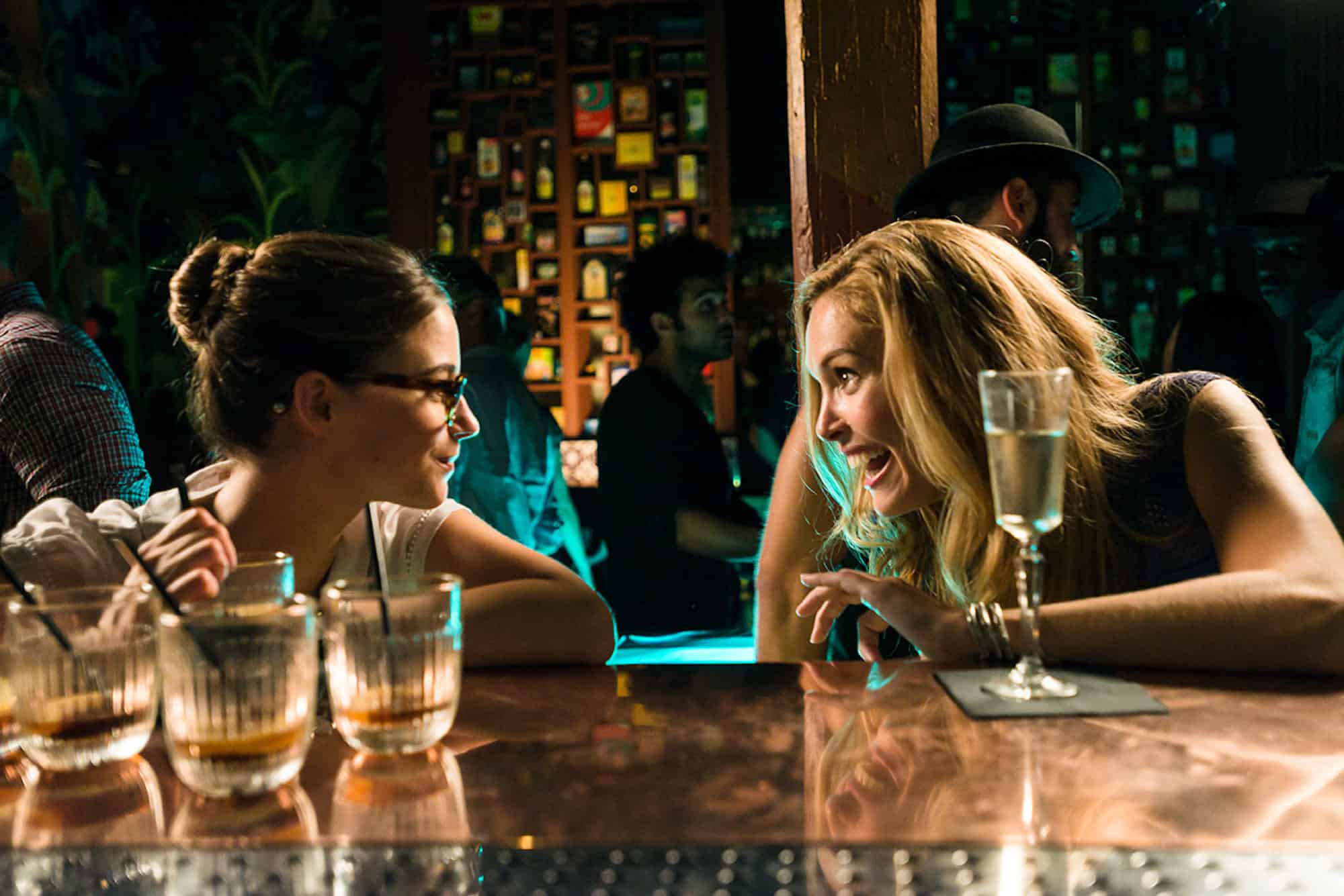 A still from the film 'Blind Date' with two women having drinks at the counter of a bar and chatting.