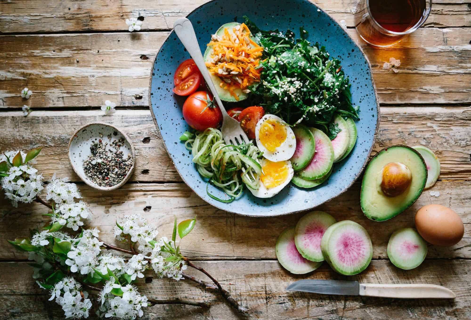 A plate of colorful gluten-free fresh salads and eggs on a wooden table