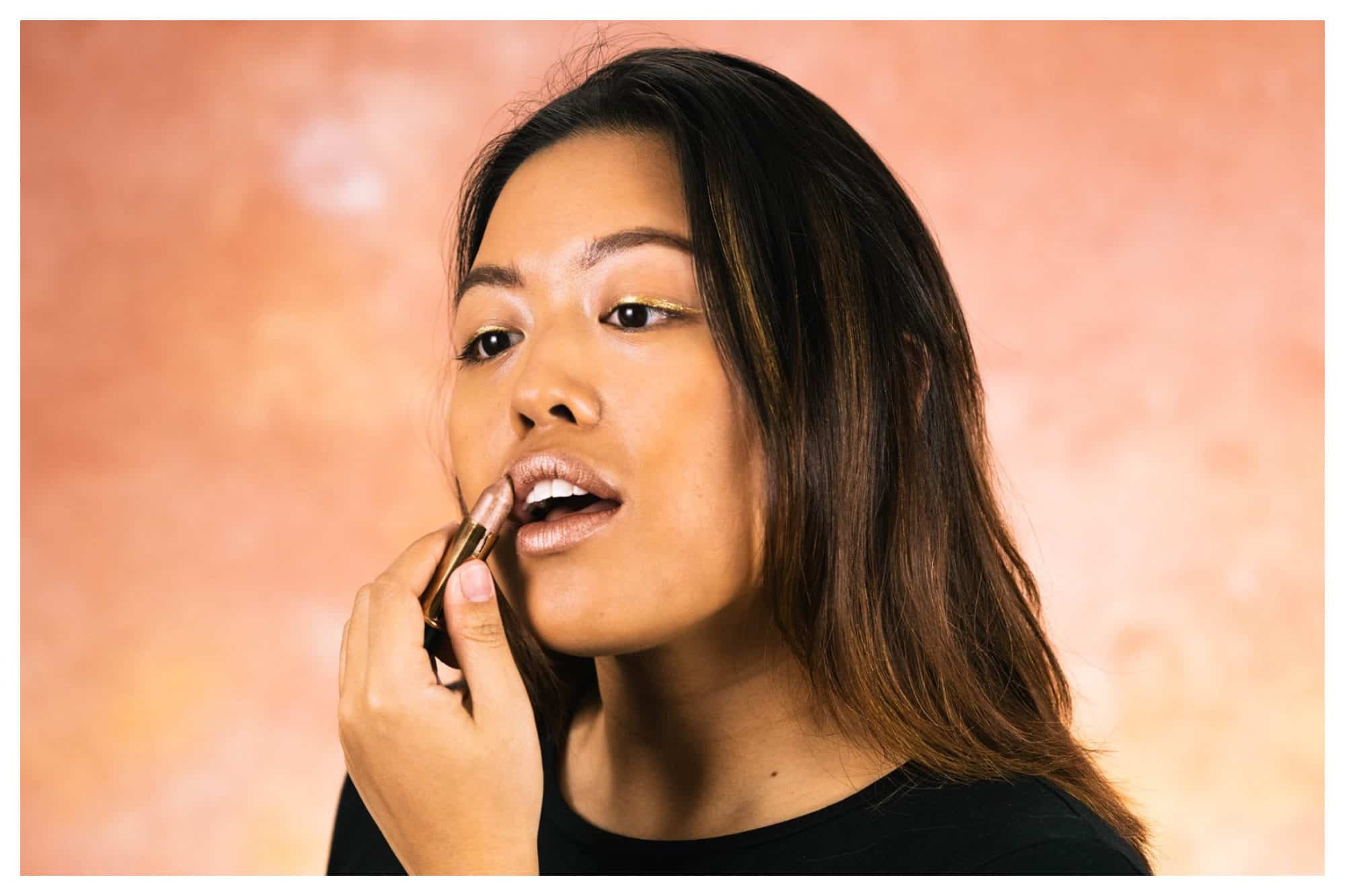 An Asia woman applying a shimmery pink lipstick from organic store Naturalia. 