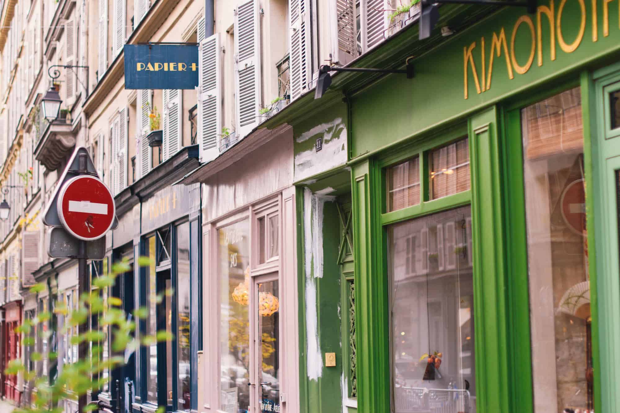 Colorful shops on a calm Paris street wait for buyers to trickle in on a sunny fall day. 