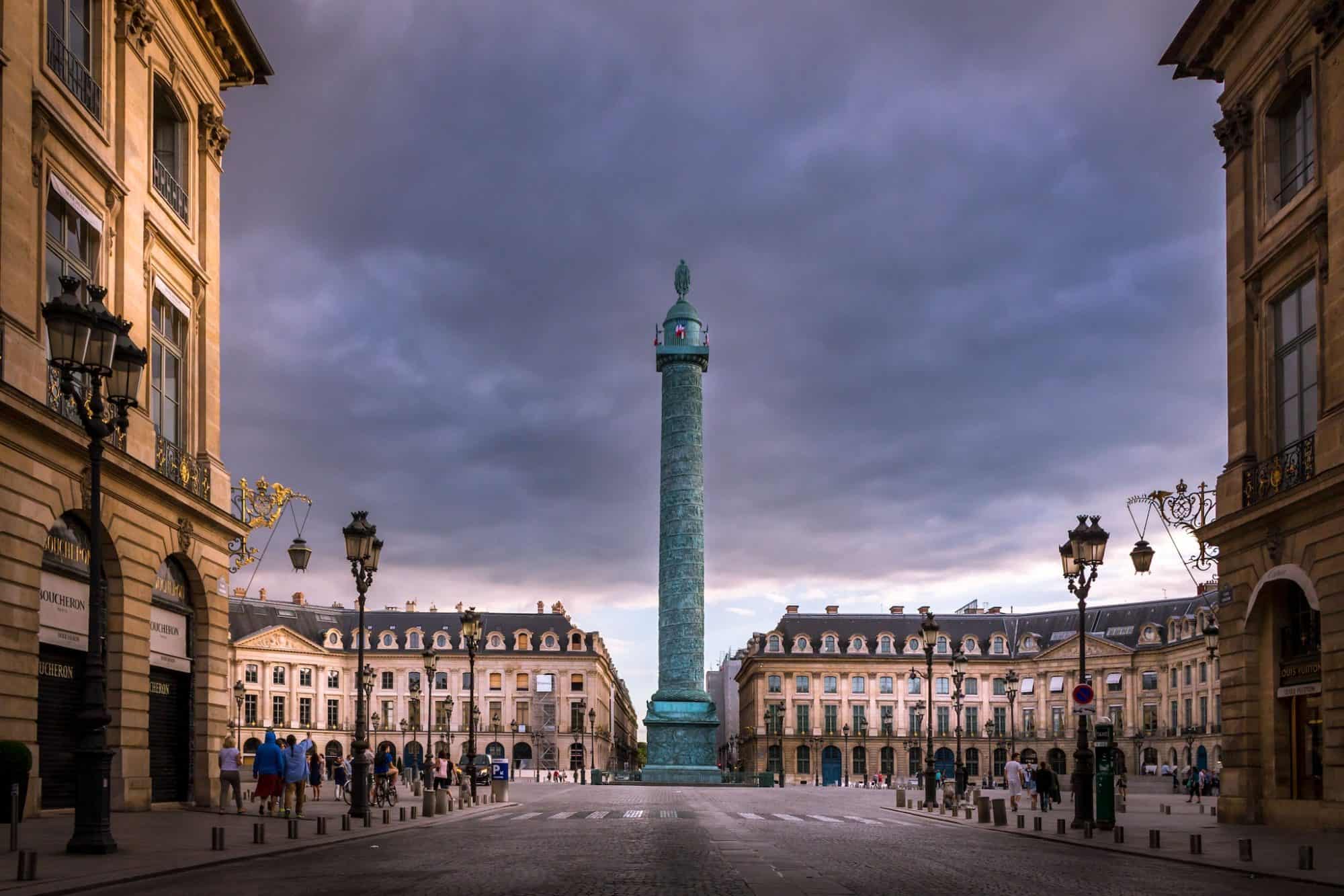 Place Vendôme during sunset under partially cloudy skies in Paris' first arrondissement. It is home to high-profile jewelry houses, including Van Cleef & carpels, Cartier, and Boucheron. 