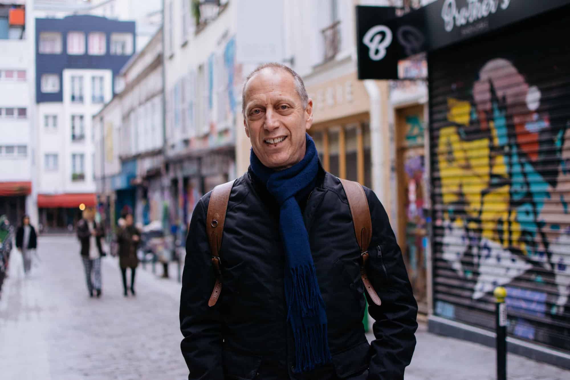 A portrait of David Lebovitz standing with a smile in the middle of a street in Paris' diverse Bellville neighborhood.