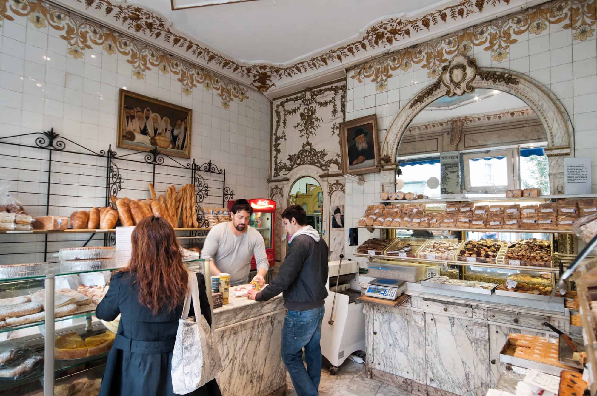 Parisian customers buy baked goods in a beautiful, bright boulangerie