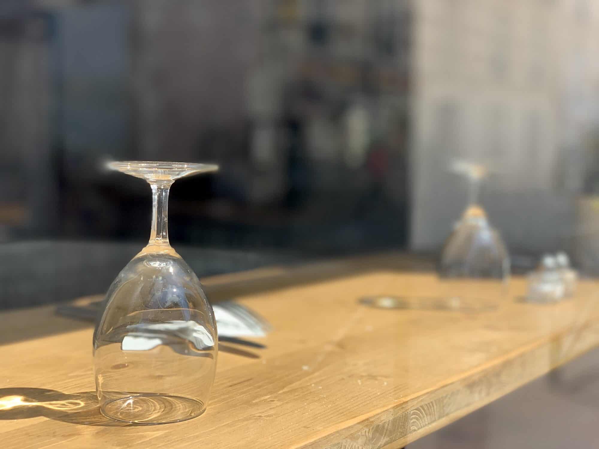 Empty wine glasses sit top-down on a tabletop in a closed restaurant in Paris.