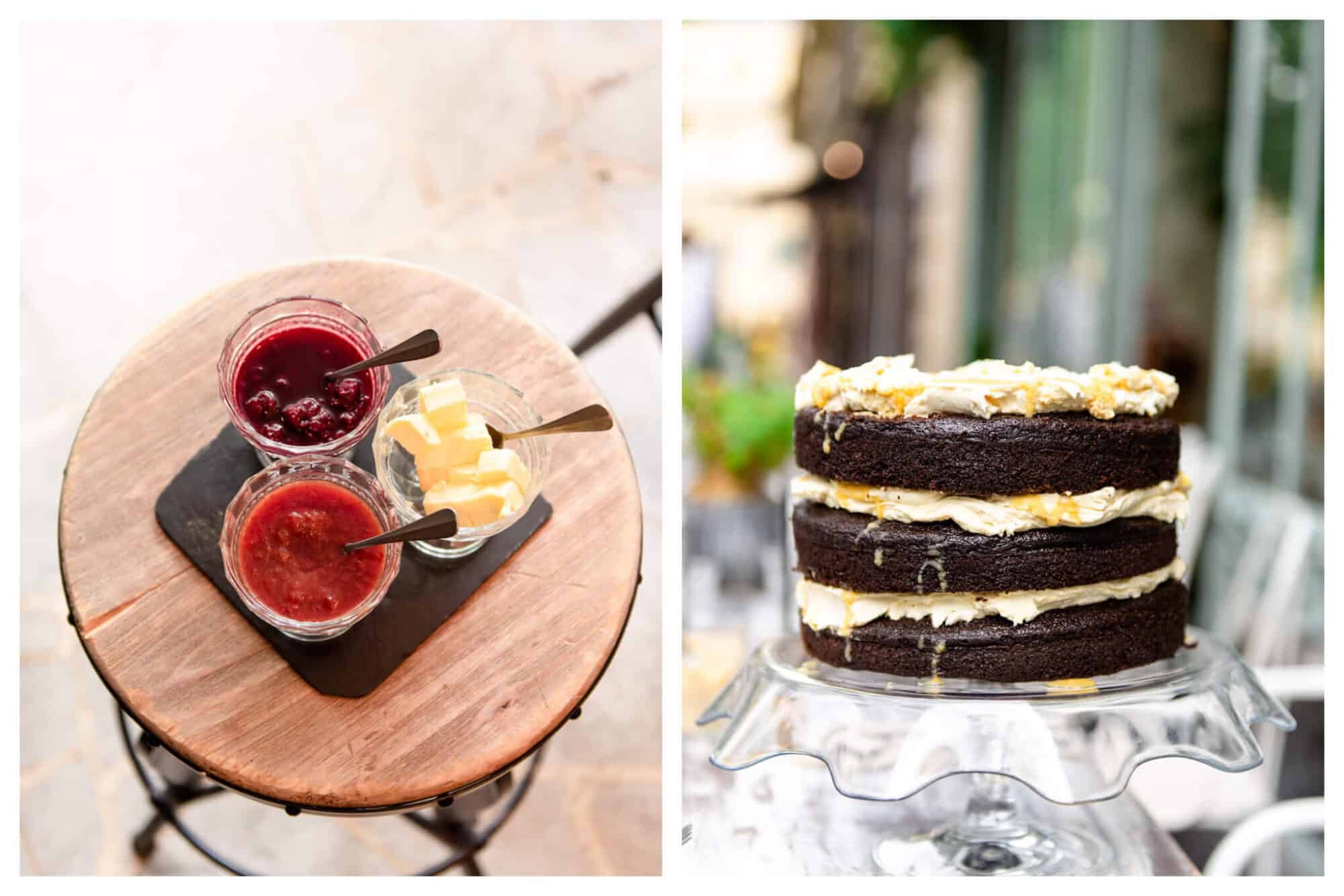 Left: Jars of red jams and a jar of butter sit atop a wooden table at Treize au Jardin, Right: A layered chocolate cake sits on a glass cake holder at Treize au Jardin