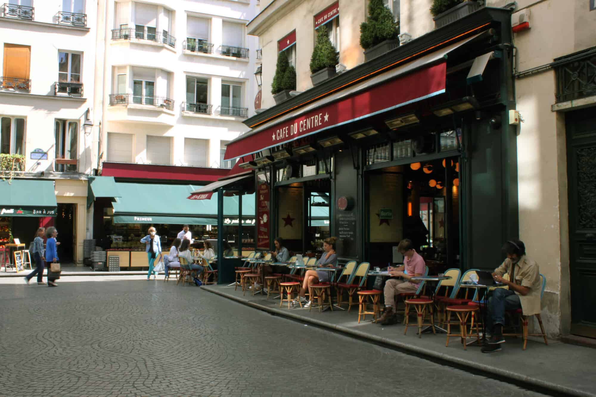 People sit socially distanced from each other at outdoor tables at a café near Rue de Montorgueil in the center of Paris.