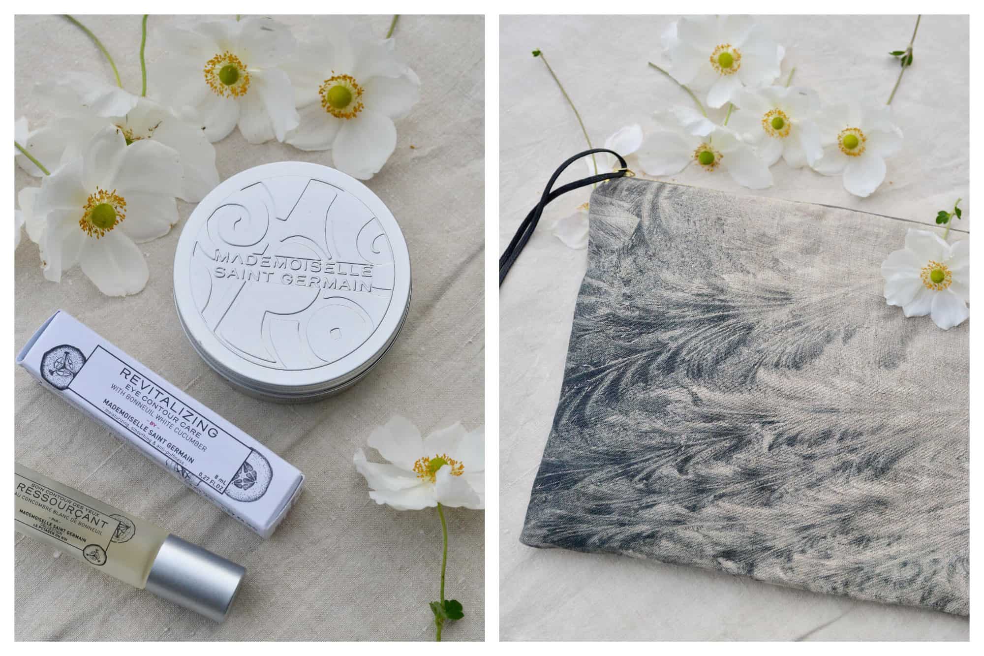 Left: an aerial view of some beauty products on a cream linen sheet with white and yellow flowers on it. There is a silver tin and a bottle of perfume as well as a product for the eyes. Right: a blue, gray, and cream pouch on a cream linen sheet. There are white and yellow flowers on it.