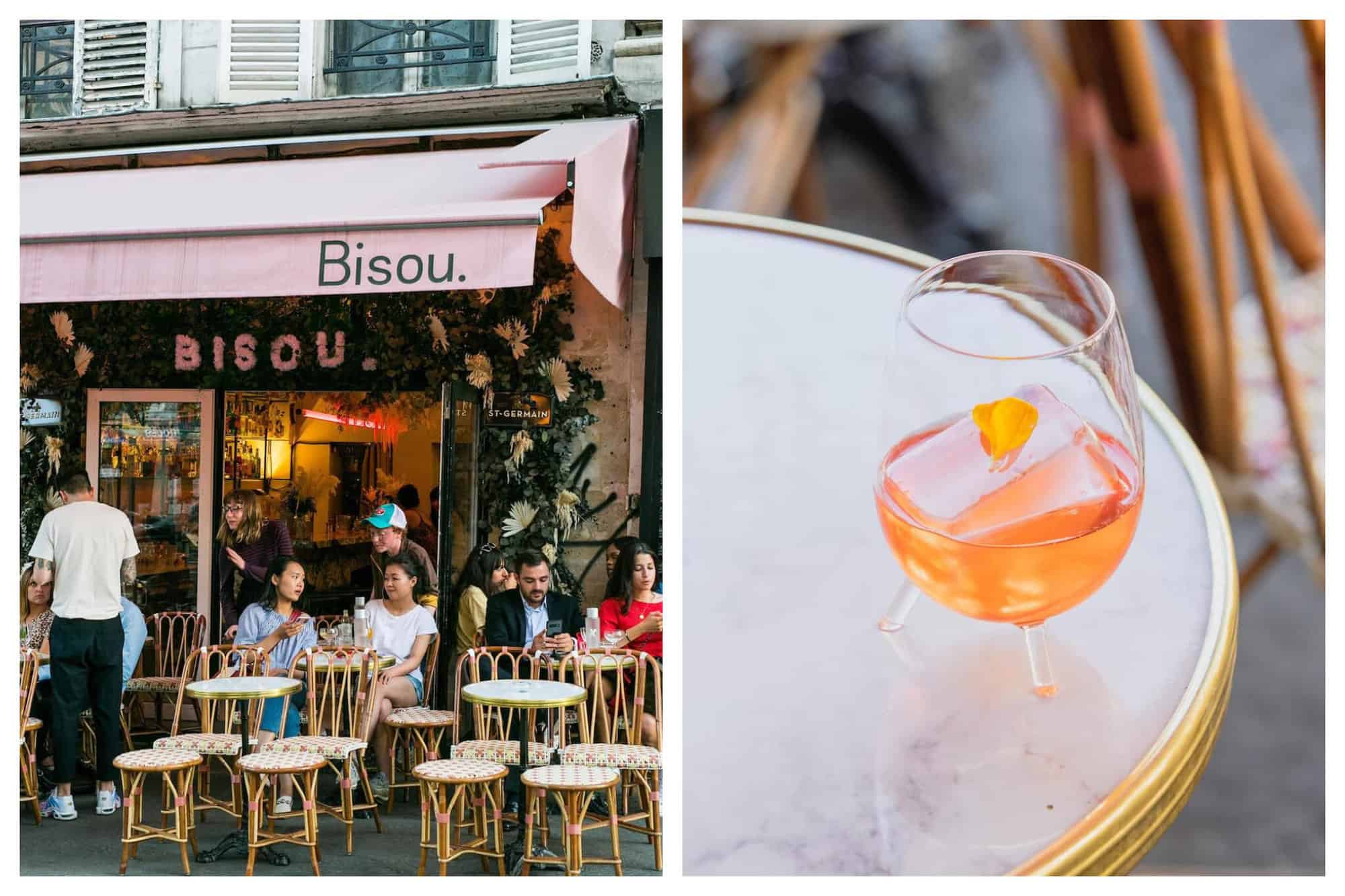 Left: the exterior of the bar in Paris called "Bisou." There is a pink awning with "Bisou." written in dark green. There are flowers and greenery on the façade of the building and there are several tables and chairs with people sitting at them. Right: An orange drink in a glass on a white marble table at "Bisou."