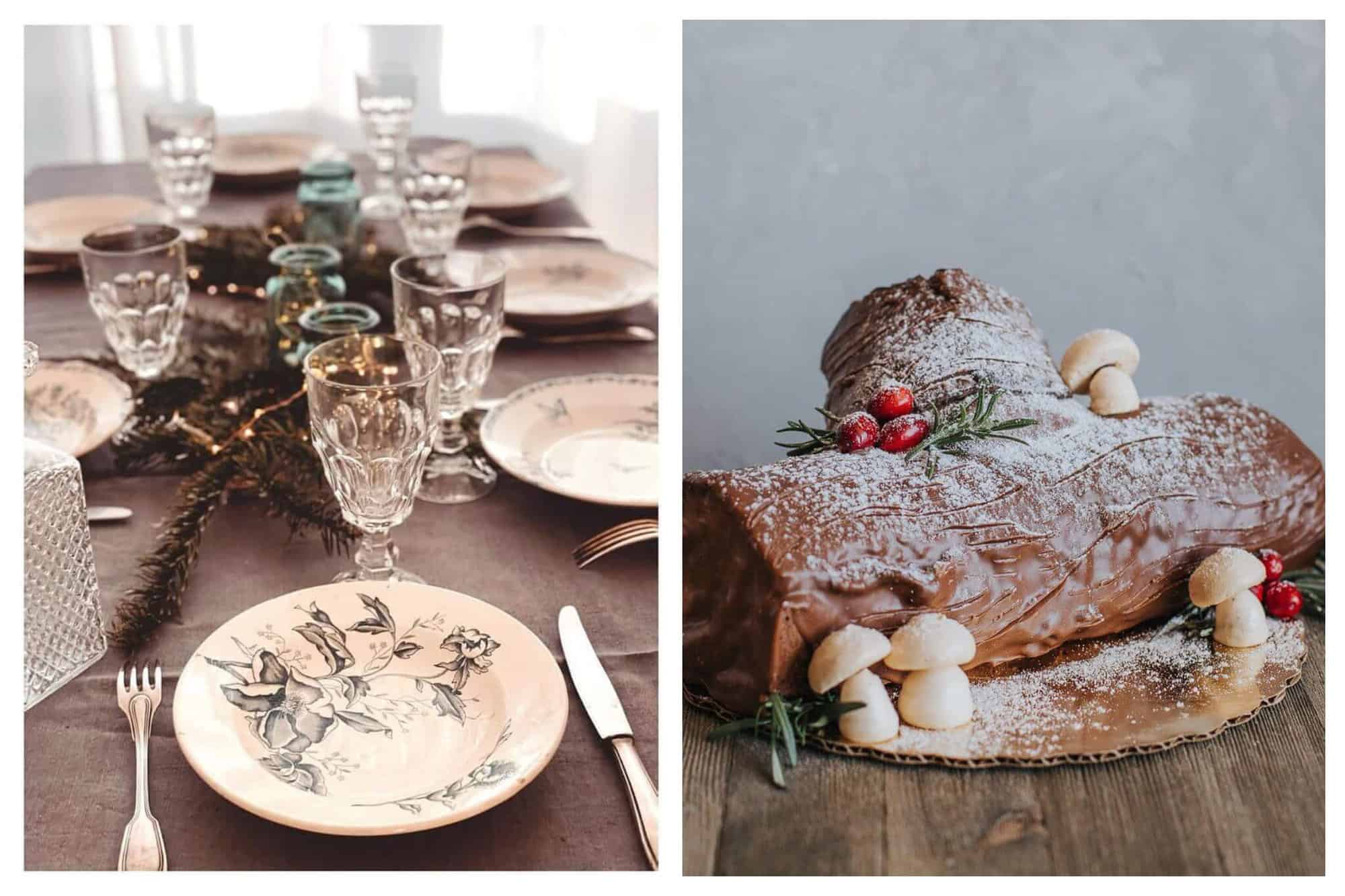 Left: a table set for a holiday meal taken from the head of the table. There are 7 plates that are white with a dark blue flower detail painted on them. There are glasses at each place setting and there is a center piece made from blue glass candle holders, fairy lights, and pine branches. Right: a buche de Noel dessert. It is chocolate and covered in powdered sugar and there are mushrooms made from sugar at the base. A few cranberries and sprigs of pine decorate the cake.