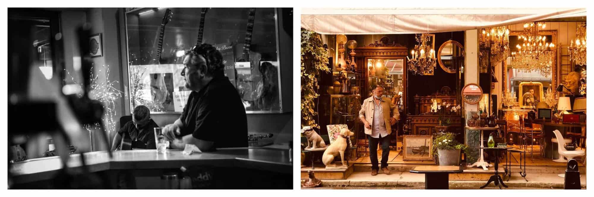 Left: A black and white photo of a man drinking a bear at the bar stand in a bar while watching live music. Right: A photo of a flea market vendor at Les Puces standing outside his shop at night, with all the chandeliers on. 