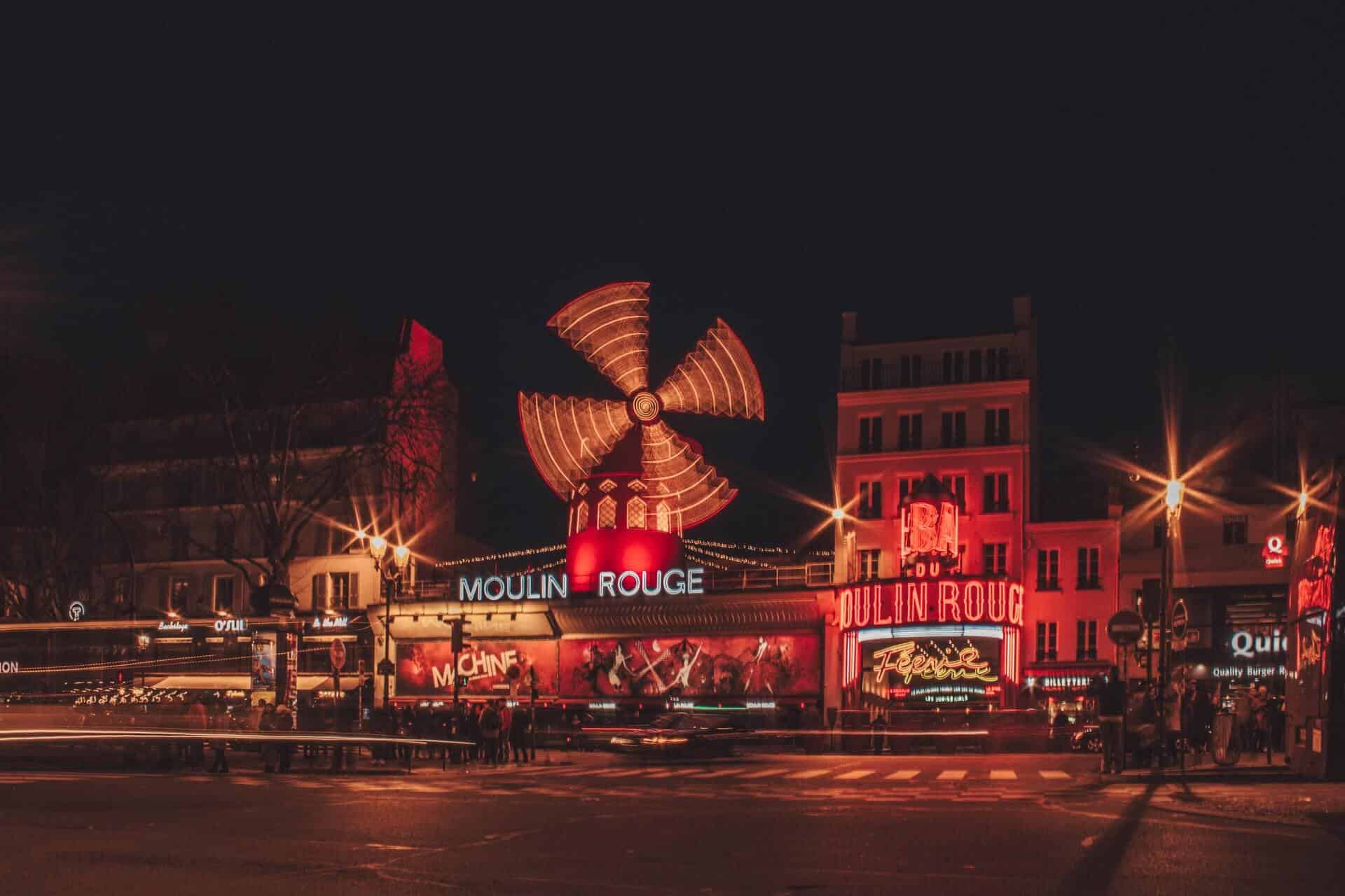 A photo of the outside of the Moulin Rouge in Paris at night.