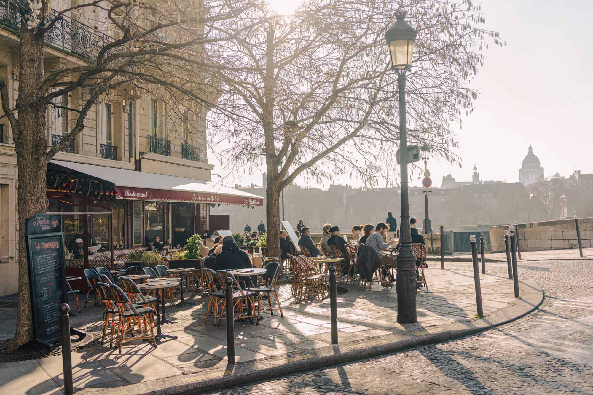 People sitting on the terrasse of a bistro on Île-Saint-Louis in Paris on a sunny winter's day.