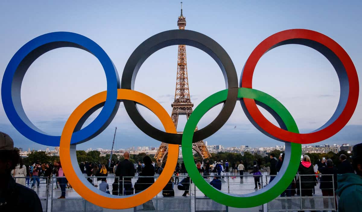 The eiffel tower behhind the Paris Olympic rings at dusk.