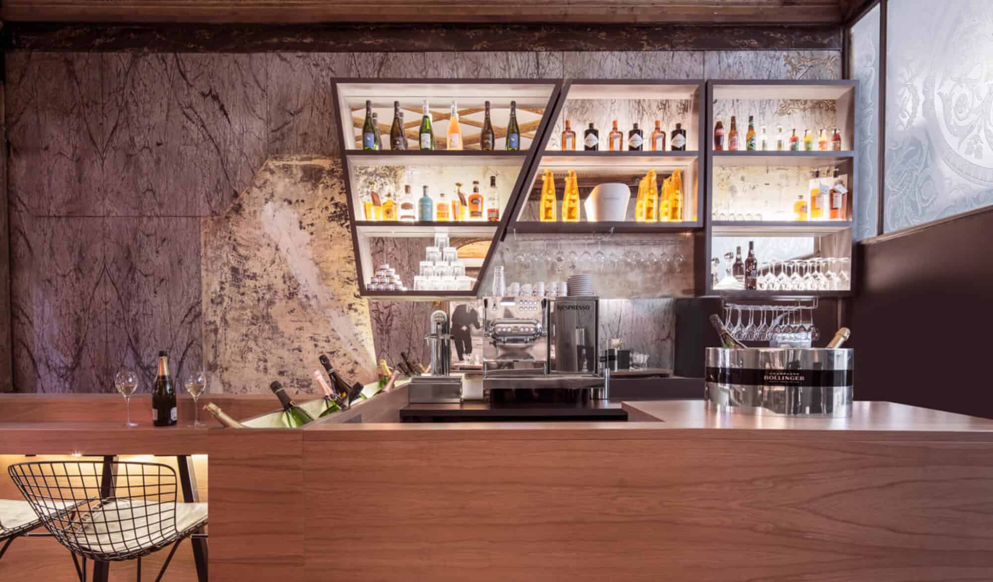 A bar counter with wooden table, silver coffee machine, and a bunch of champagne chilled in ice.