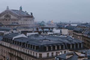 A gloomy day in Paris with a foggy sky overlooking the gray rooftops of buildings.