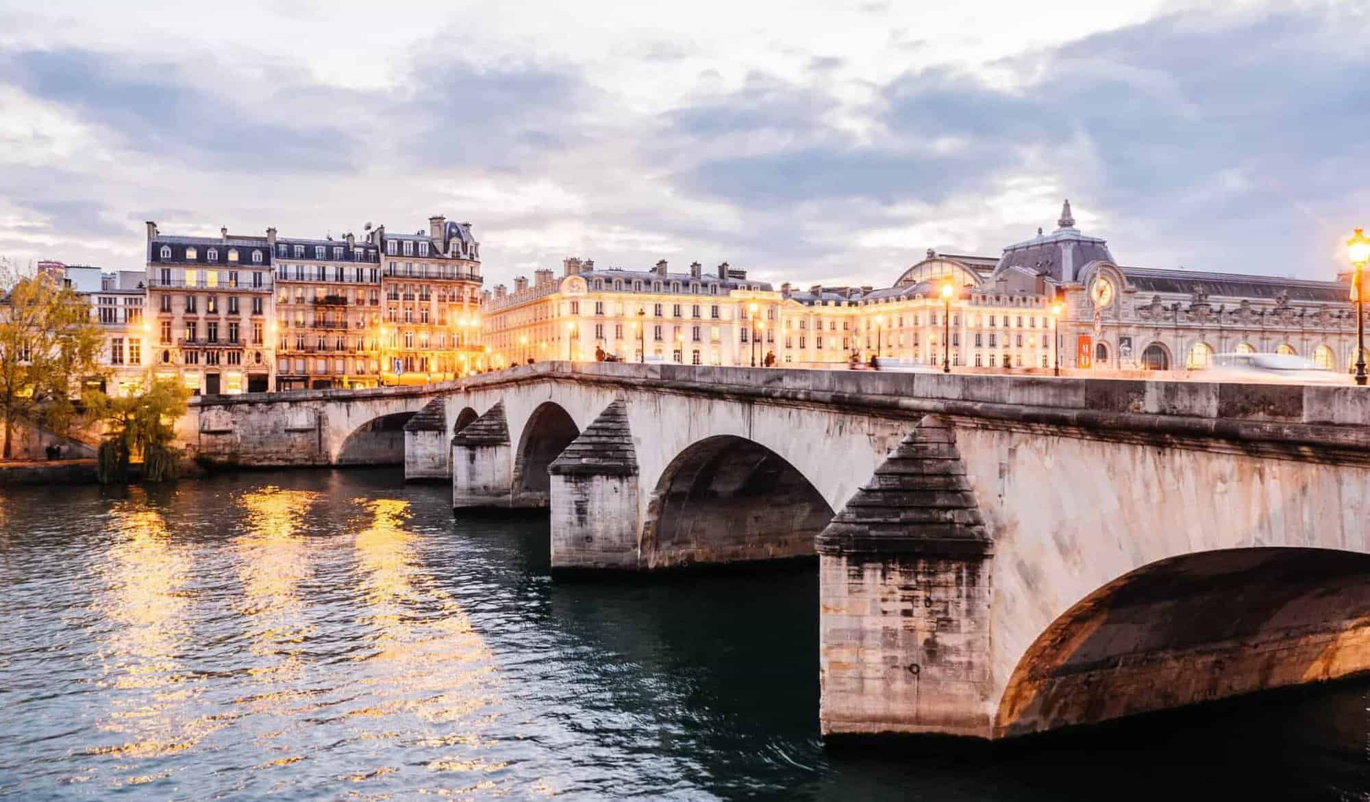 The Pont Royal bridge on the river seine and surrounding Parisian buildings during sunset.