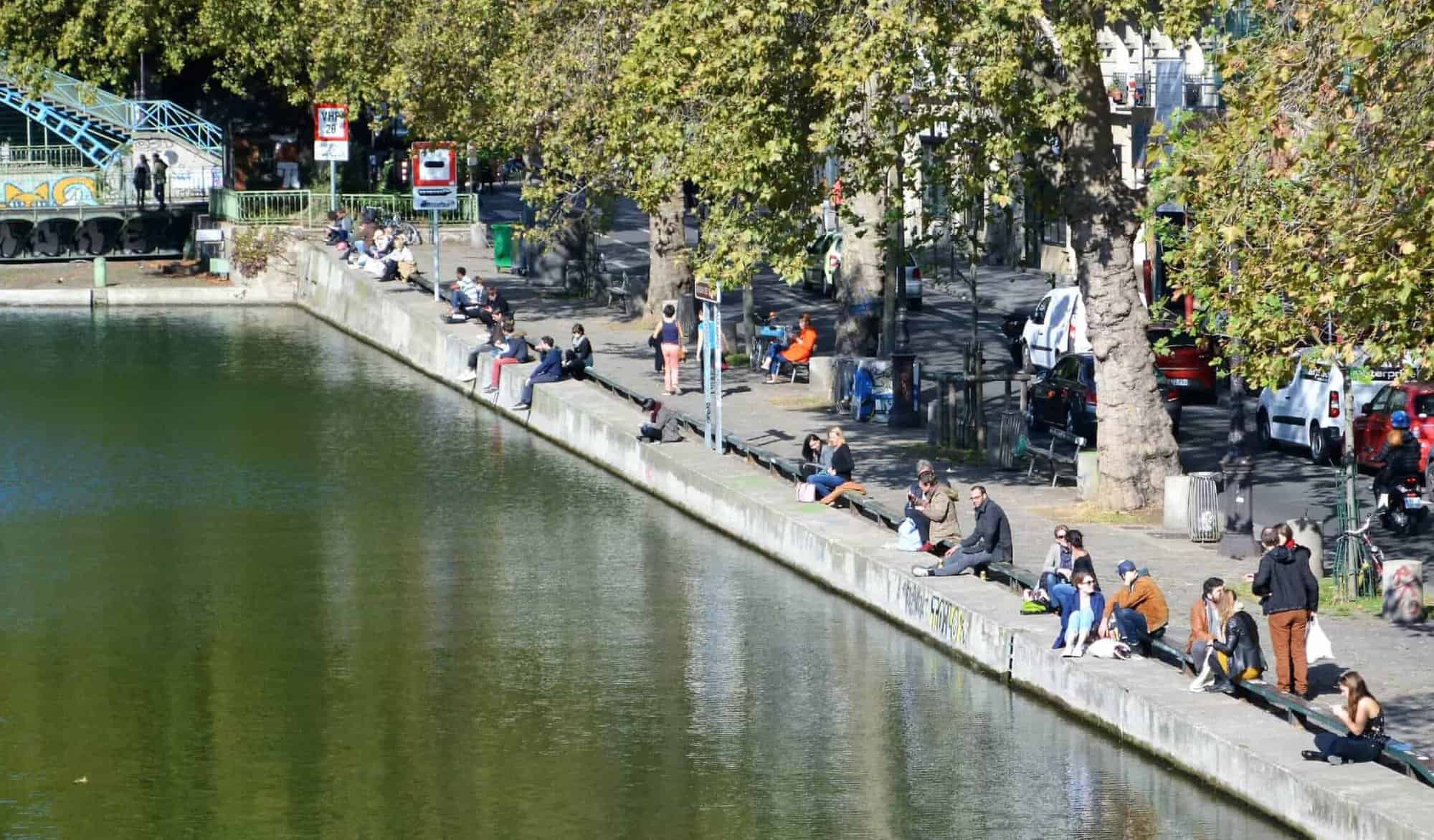 People sitting by a canal on a sunny day.