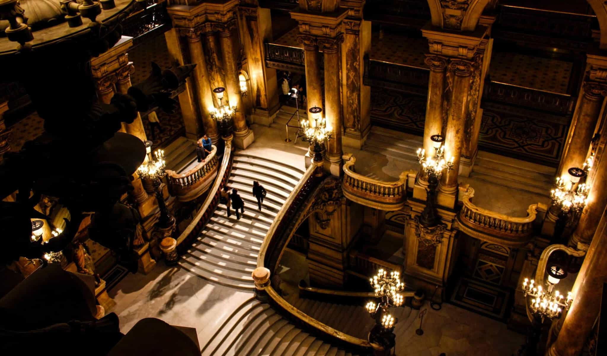 The inside of the Opera Garnier in Paris, full of marbled stairs and golden lights.