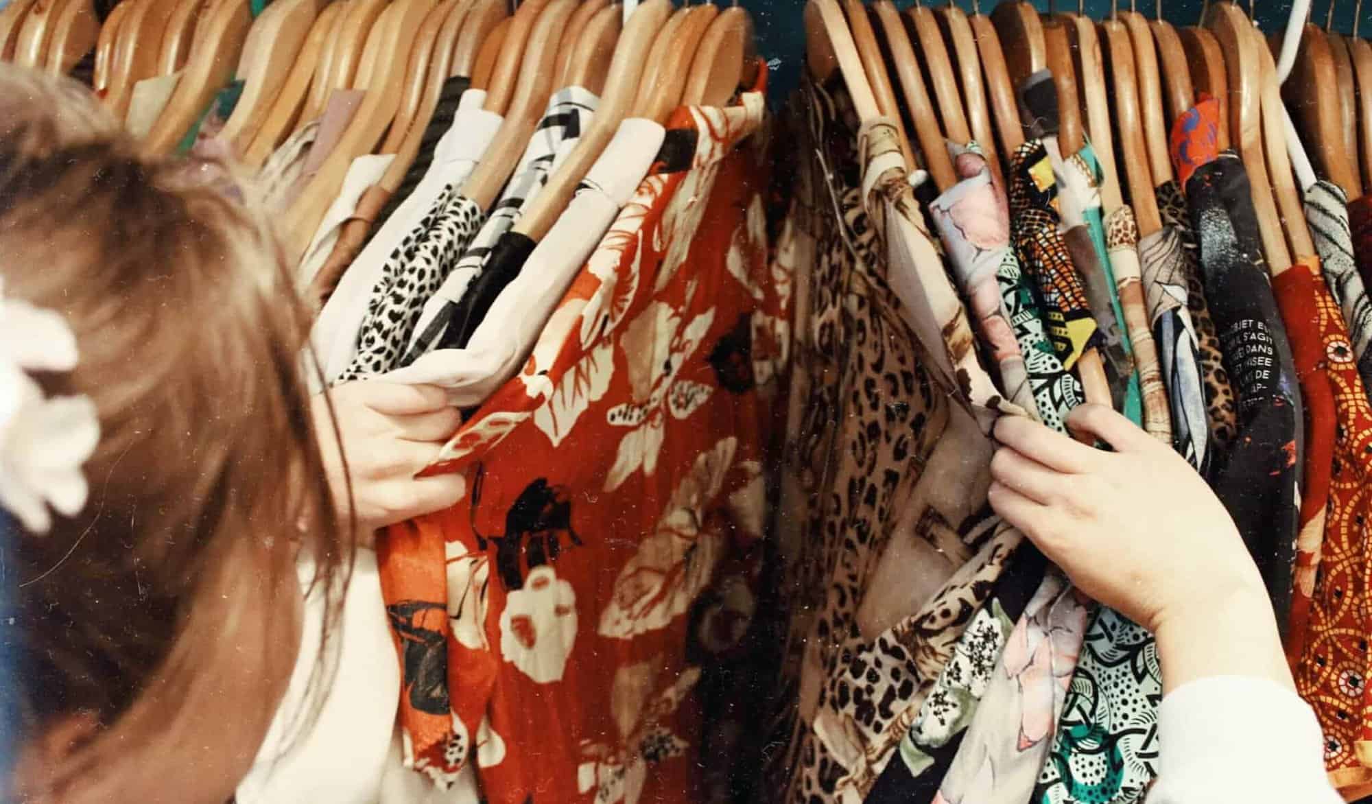 A girl browses through a stack of clothes.