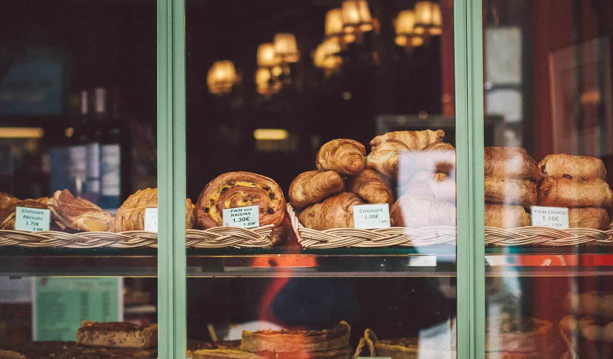 French bread and pastries are lined in a bakery window.