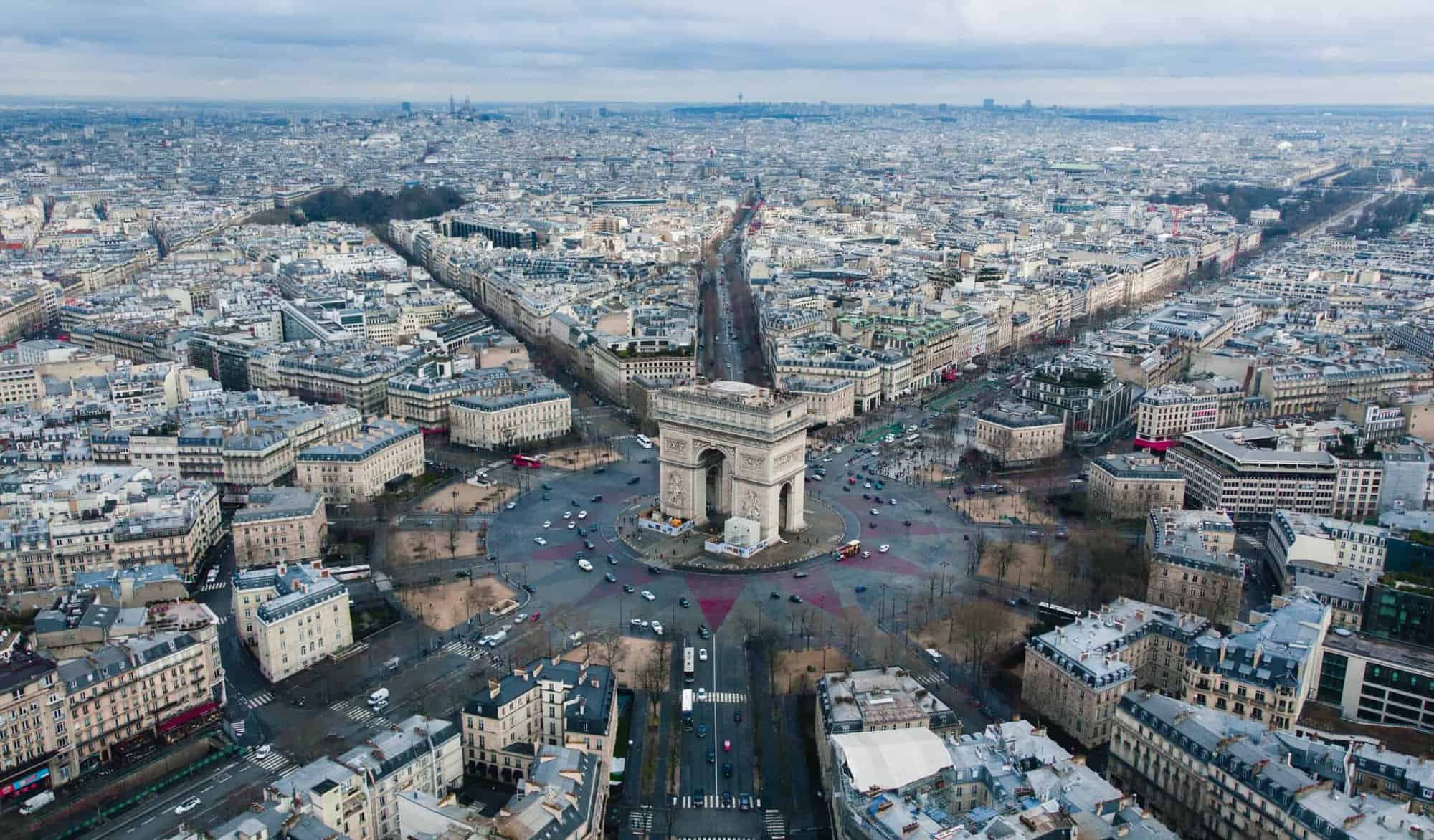 An aerial view of the Arc de Triomphe in Paris on a gloomy day.