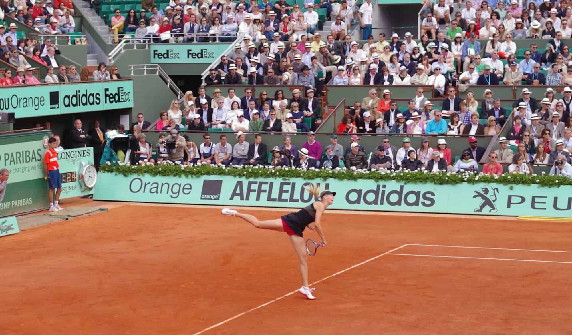 At this one match in Roland Garros or the French Open, a female tennis player serves in her black outfit as a crowd of spectators watch.