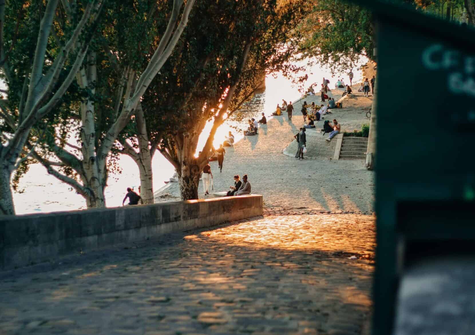 People strolling along the Seine river at sunset.