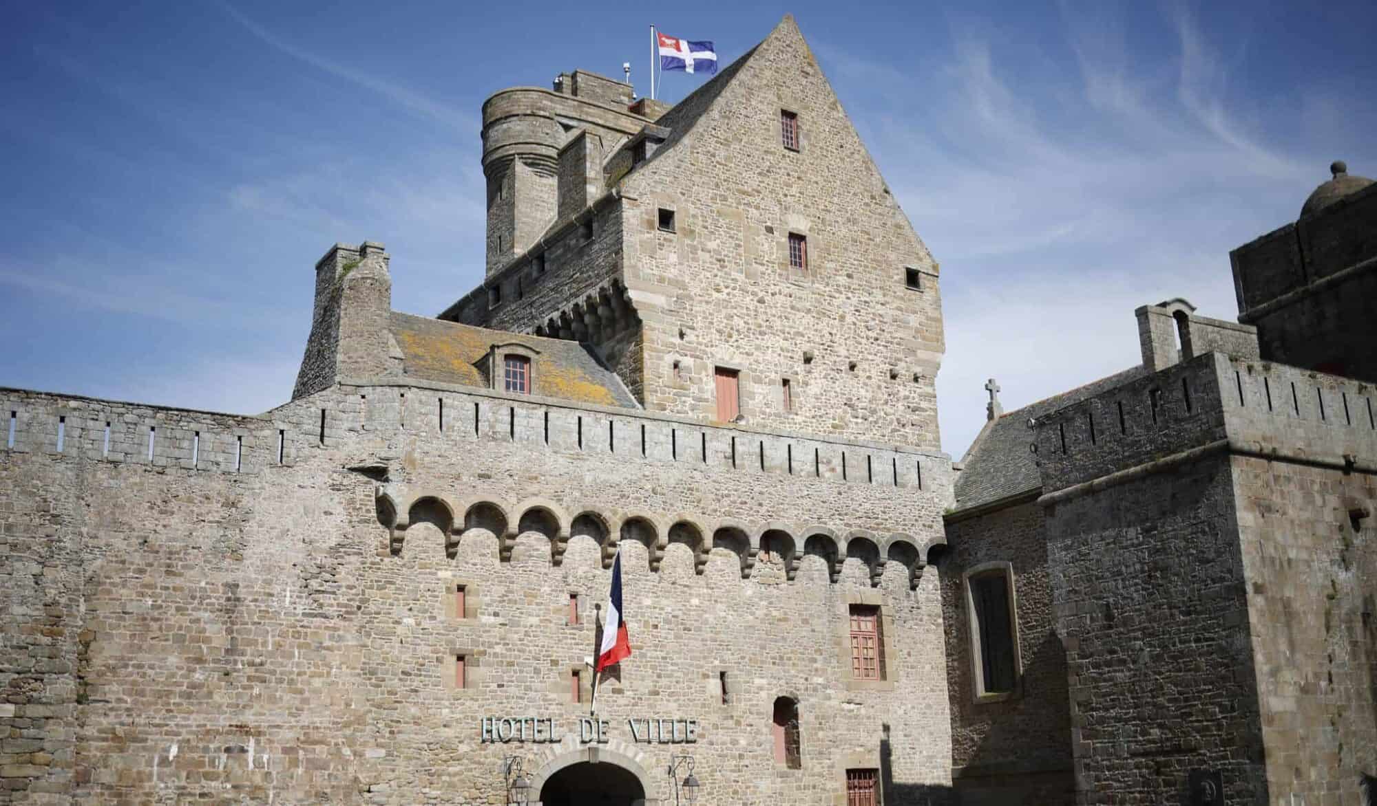 Saint Malo's Hotel de Ville or town hall with its medieval-styled bricks and the flags of France and Brittany.