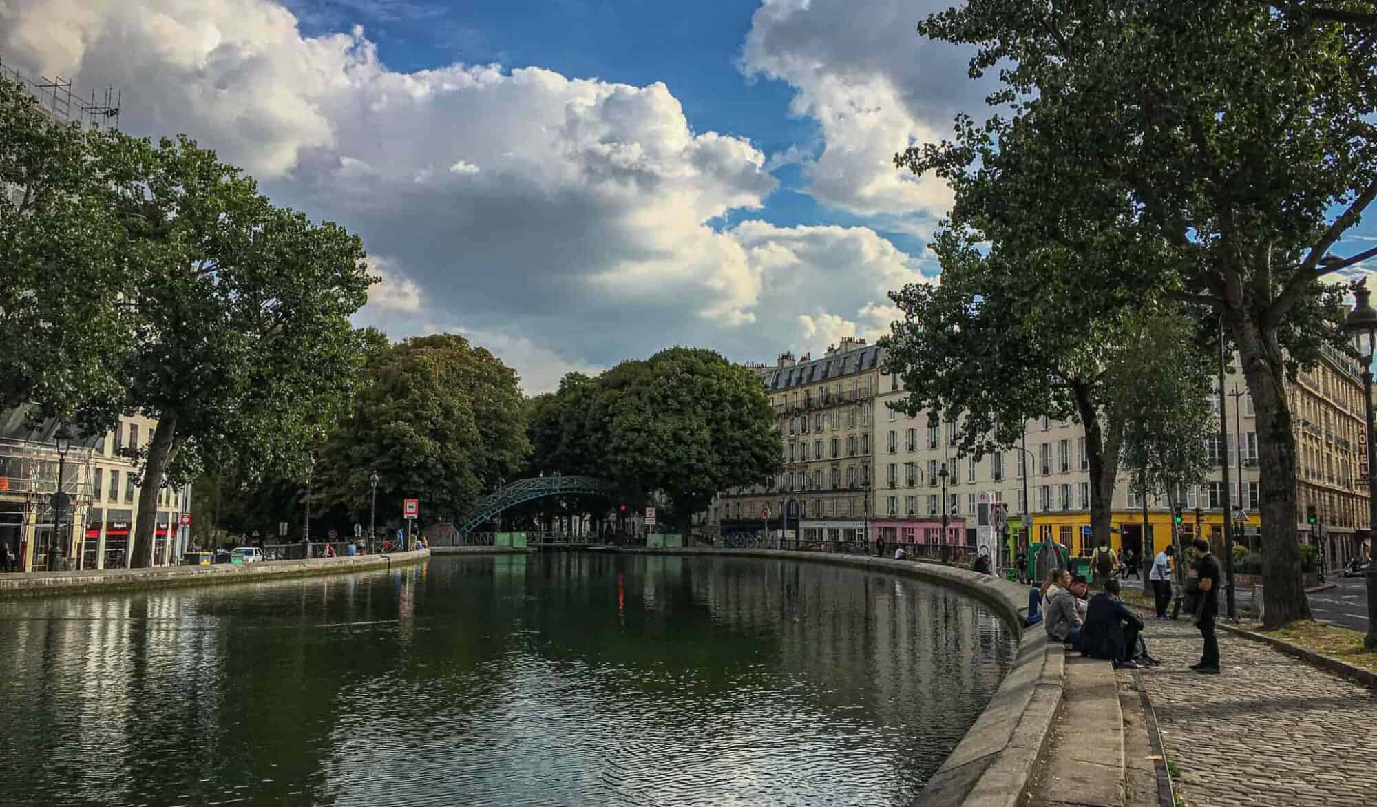 Parisians sit by the edge of the Canal Saint Martin on a summer day.