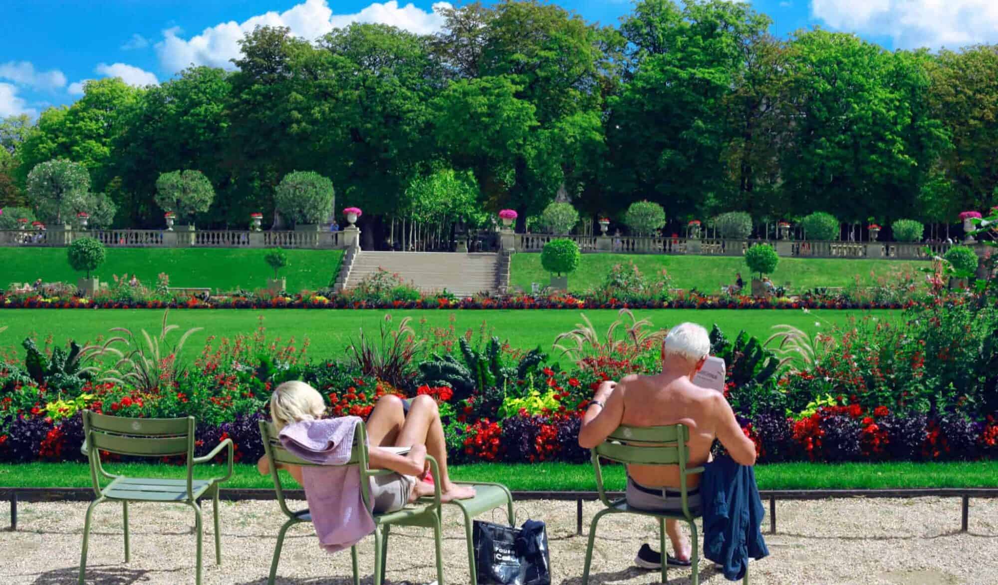 An elderly man and woman sitting on green chairs in Jardin du Luxembourg in Paris.