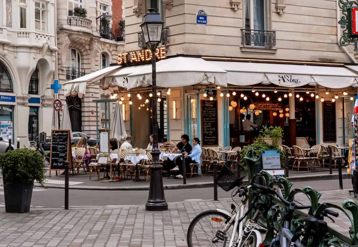 O terraço do restaurante St Andre em Paris, com luzes penduradas em seu toldo branco em um dia nublado. 