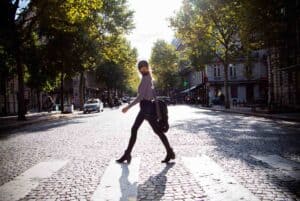 A woman crosses a Parisian boulevard in the middle of summer.