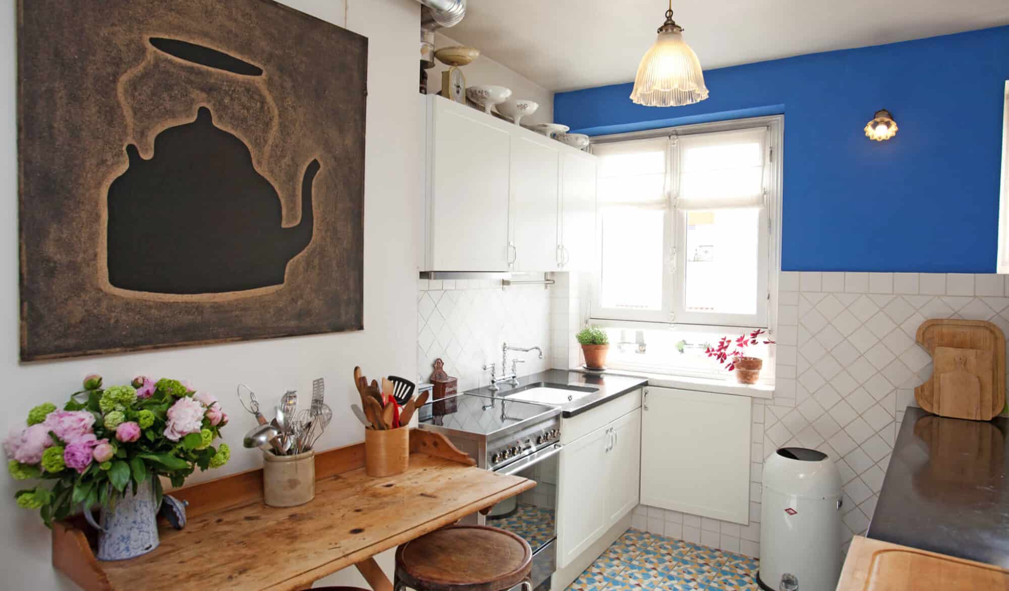 A kitchen in a Parisian apartment with white cabinets and a brown wooden table.