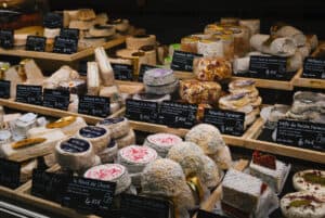 A display of dozens of types of French cheeses at a market stall.